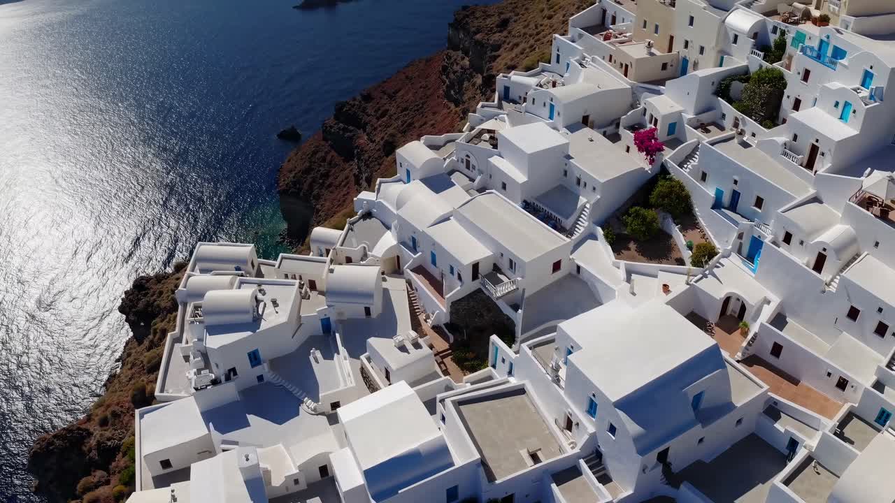 Capturing the stunning beauty of Santorini, Greece, with whitewashed buildings perched on a cliffside, overlooking the deep blue Aegean Sea under radiant summer sunlight
