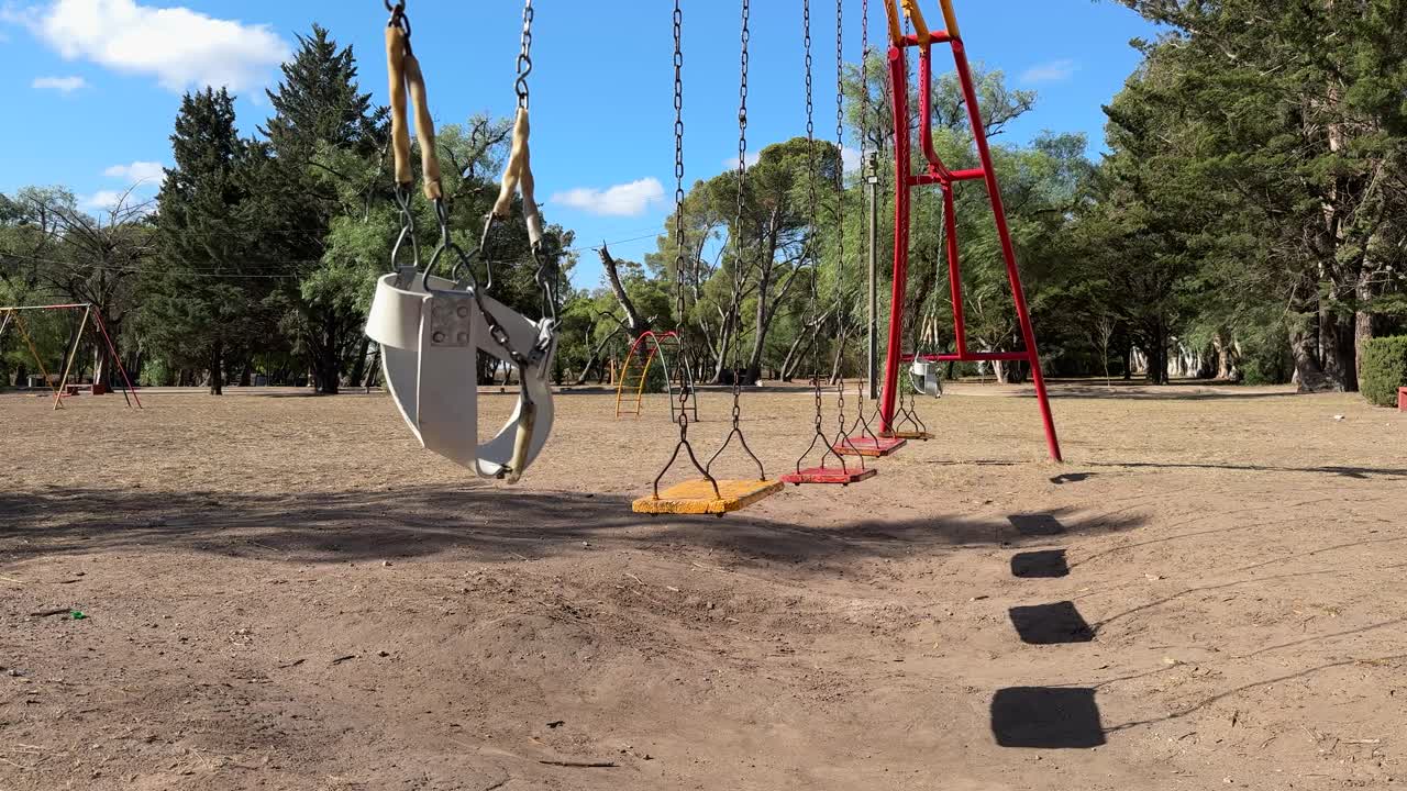 Empty Swings Swinging On A Windy Day At The Children's Playground. - static shot