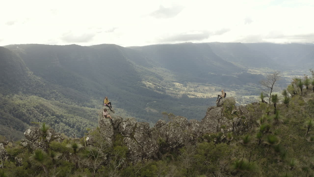 4k Drone shot orbiting people on a trail path with big rocks on a mountain spine. Taking a rest after a long hike at Border Ranges National Park, New South Wales Australia.