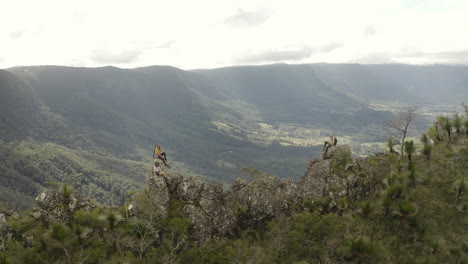 4k drone shot orbiting people on a trail path with big rocks on a mountain spine. taking a rest after a long hike at border ranges national park, new south wales australia.