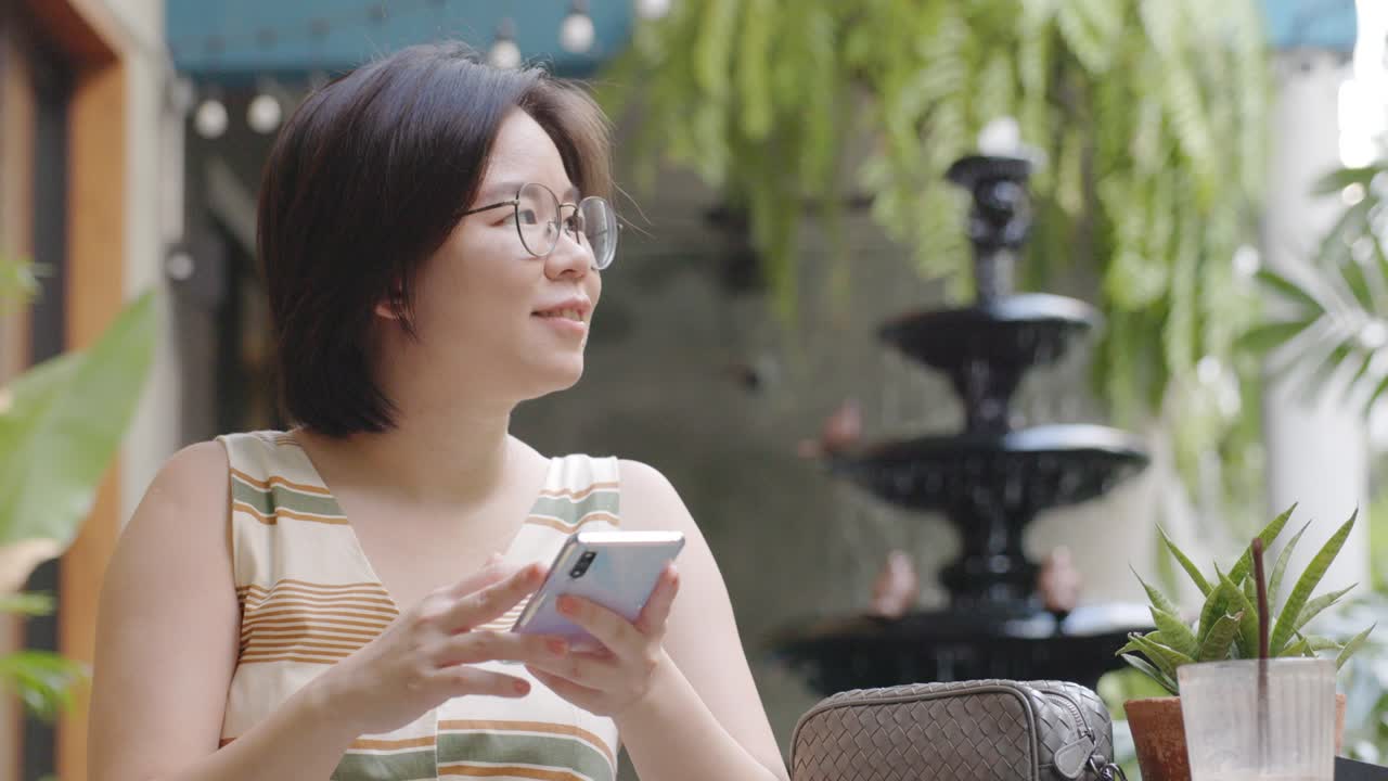 카페에 앉아 여행을 찾기 위해 온라인 쇼핑과 소셜 미디어에서 터치 스마트폰을 사용하는 여성 짧은 머리카락, 안경을 입은 관광객.