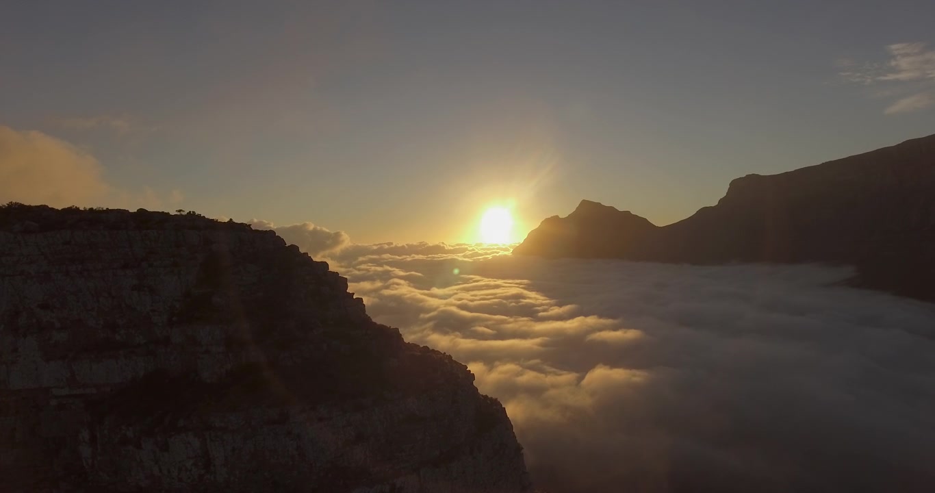 Toma de dron durante el amanecer sobre la Montaña de la Mesa y la Montaña Cabeza de León en Ciudad del Cabo, Sudáfrica, con nubes en el valle en una mañana soleada LOG