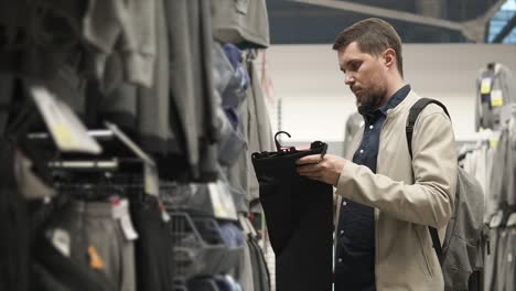 man shopping for pants in a clothing store