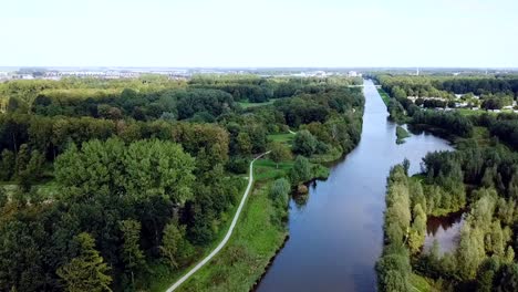 drone flying over the canal in the forest with a village in the background