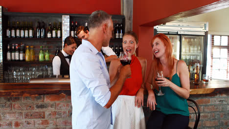 three friends with wine glass talking to each other at counter