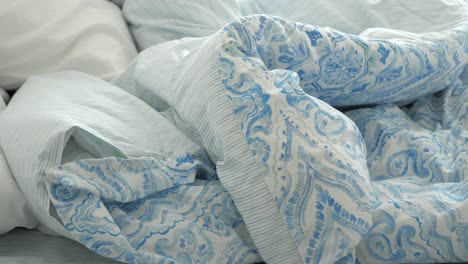 unmade bed with blue and white bedding