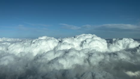 pov flying over a layer of stratus clouds with a deep blue sky. a pilot’s perspective from an airplane cockpit. 4k 60fps