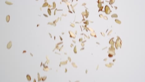 sliced almond nut pieces raining down on white backdrop in slow motion