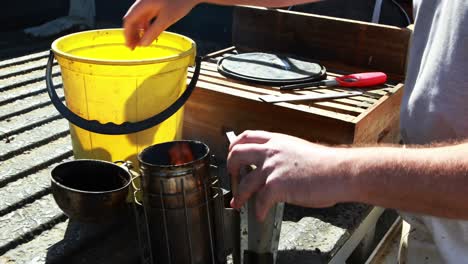 Beekeeper-preparing-smoker-for-harvesting-in-apiary