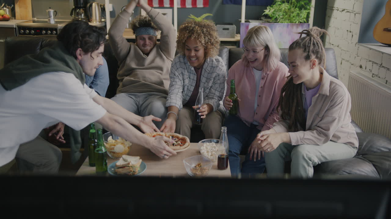 Friends Enjoying Pizza and Drinks in Front of TV