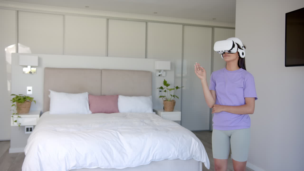 Using VR headset, woman exploring virtual reality in modern bedroom, copy space