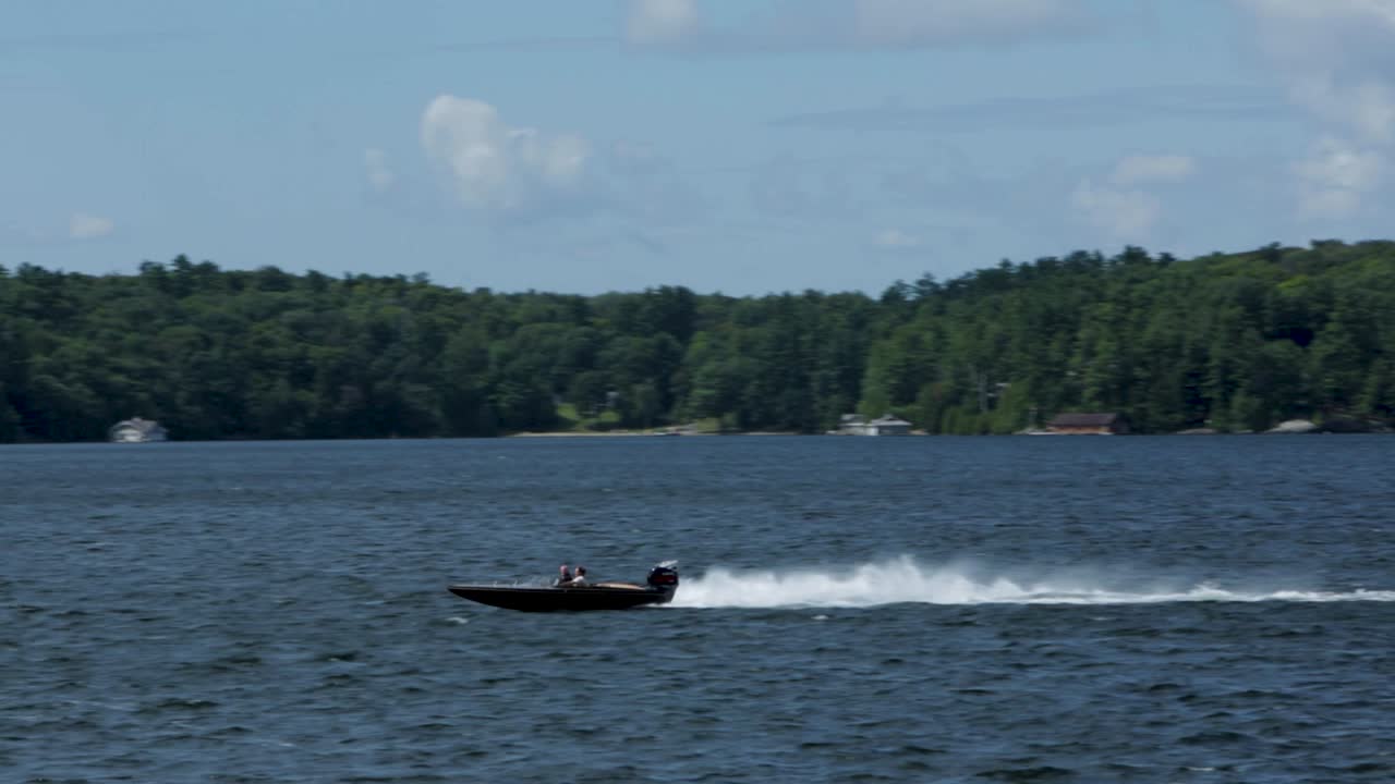 Fast boat speeding along Muskoka Lake. Travelling Right to left