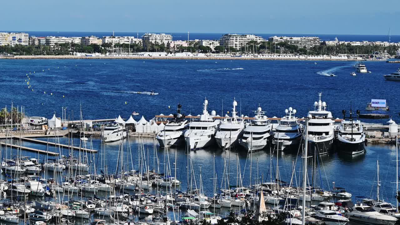 View of the sea port of Cannes, France. Moored and moving yachts, buildings, greenery, Mediterranean sea