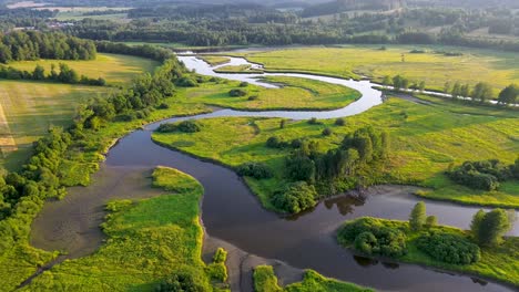 cinematic drone view of a blue river flowing through a green landscape in the countryside