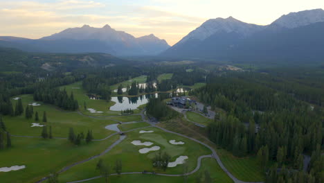 drone aerial view over green golf course in the rocky mountains of banff and kananaskis of alberta, canada at sunrise