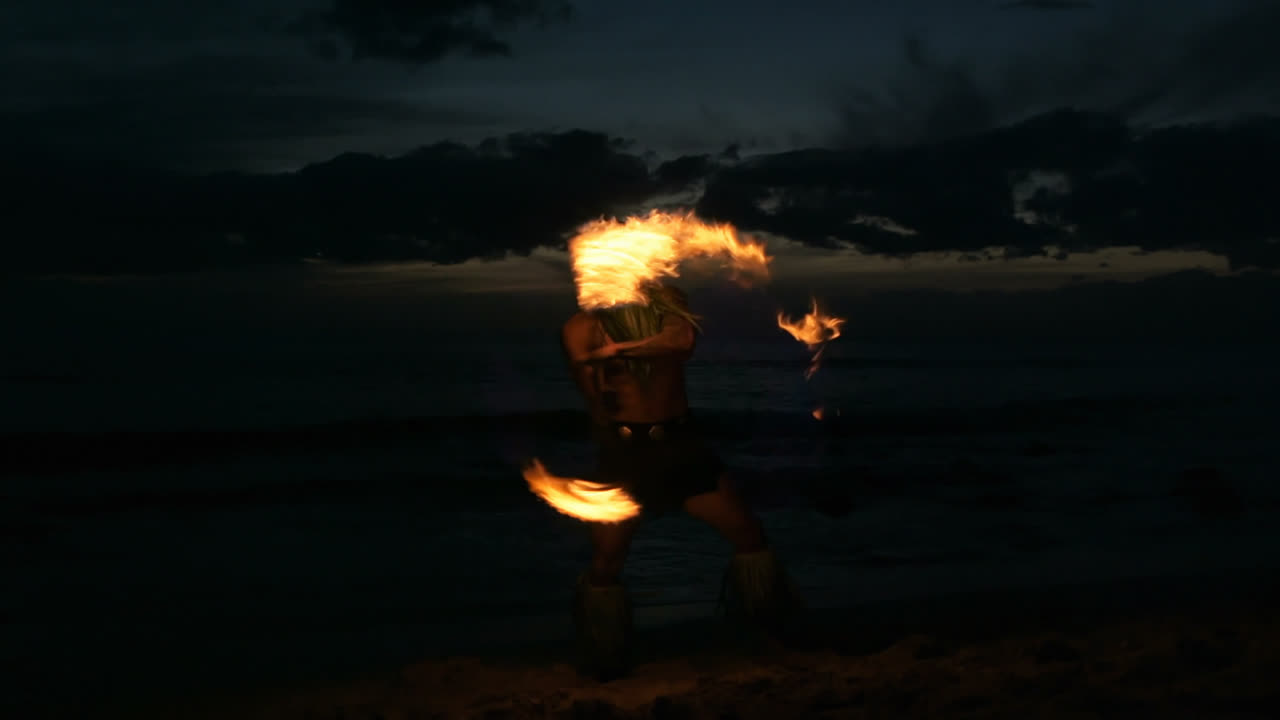 Fire juggler juggling fire sticks in the beach 4k