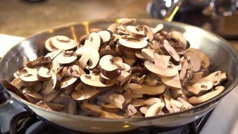 Un-Montón-De-Champiñones-En-Rodajas-Que-Chisporrotean-En-Una-Sartén-De-Acero-Inoxidable