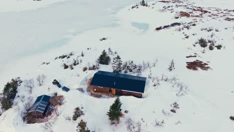 aerial view of mountain cabin surrounded by thick snow at winter