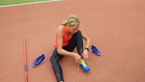 Vista-De-ángulo-Alto-De-Una-Atleta-Caucásica-Atando-Cordones-De-Zapatos-En-Un-Recinto-Deportivo-4k