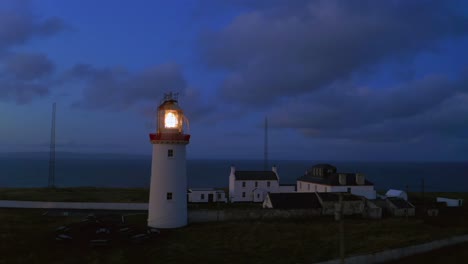 panela aérea de la baliza del faro brillando justo antes del amanecer