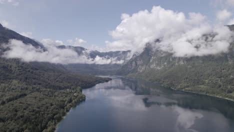video de drone frontal sobre el lago bohinj avanzando hacia su interior entre las montañas, el cielo está despejado con algunas nubes