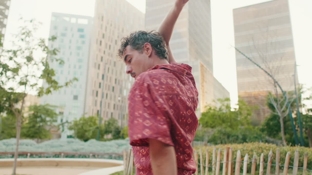 Young Man Performing Expressive Dance in Modern City Park