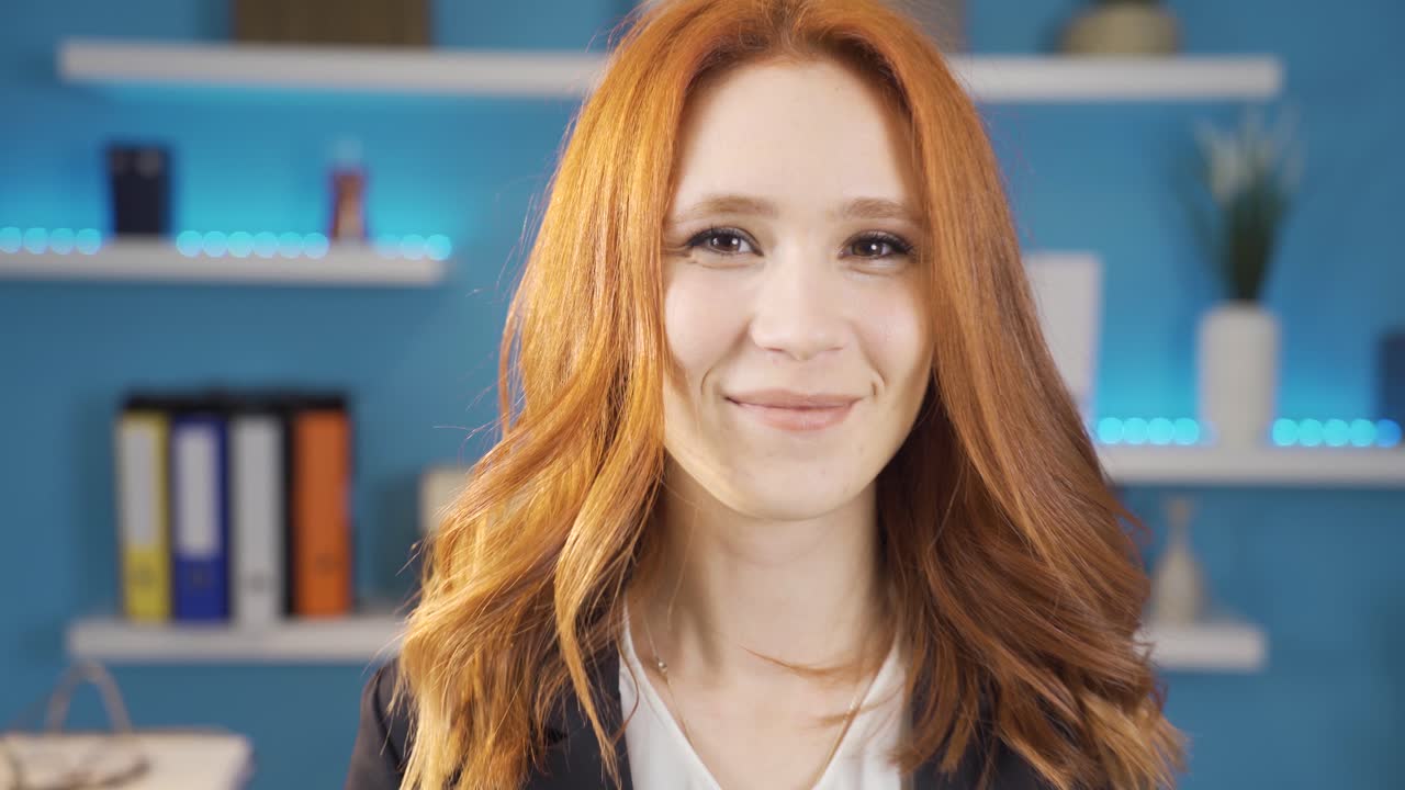 젊은 사업가 여성이 일을 끝내면서 행복하게 카메라를 쳐다보고 있습니다.