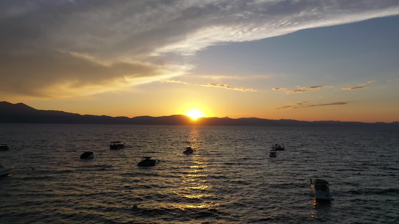 Small Boats Floating In The Lake Tahoe During Golden Hour Of Sunset. - aerial approach