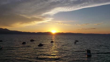 small boats floating in the lake tahoe during golden hour of sunset. - aerial approach