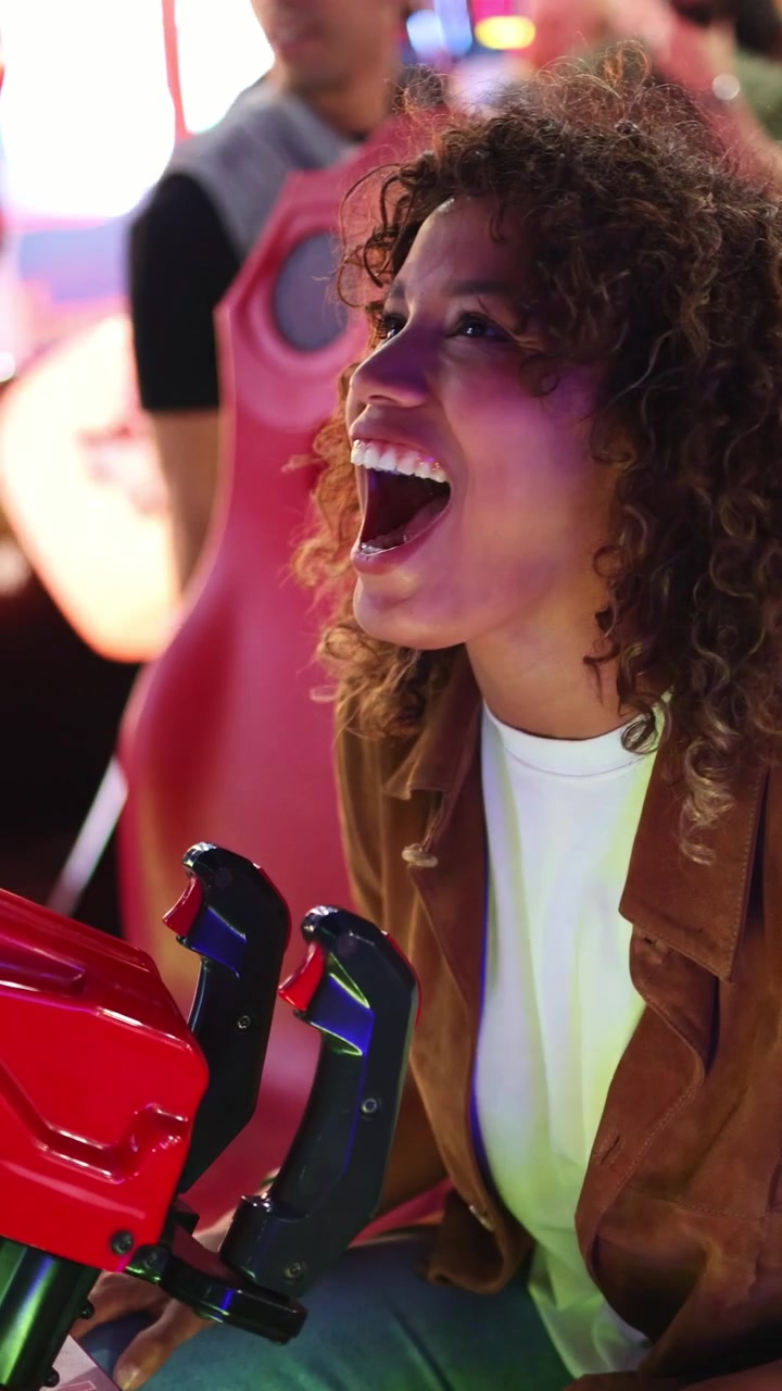 Giovane donna felice che ride mentre gioca a un videogioco arcade