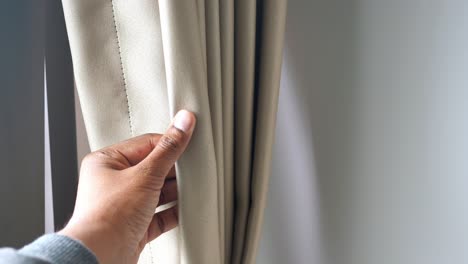 person opening a beige curtain