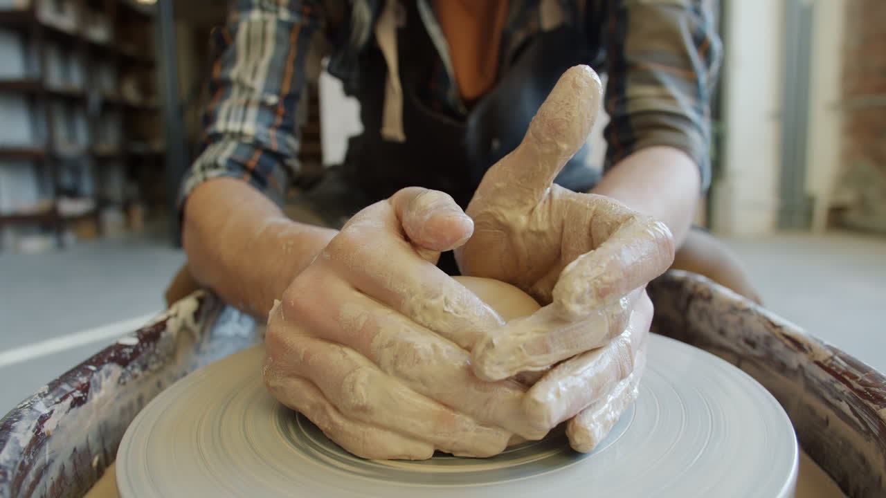 manos moldeando arcilla en una rueda de cerámica