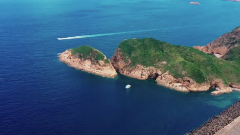 aerial tracking view boat sailing off the coast of lush tropical sai kung island landscape hong kong