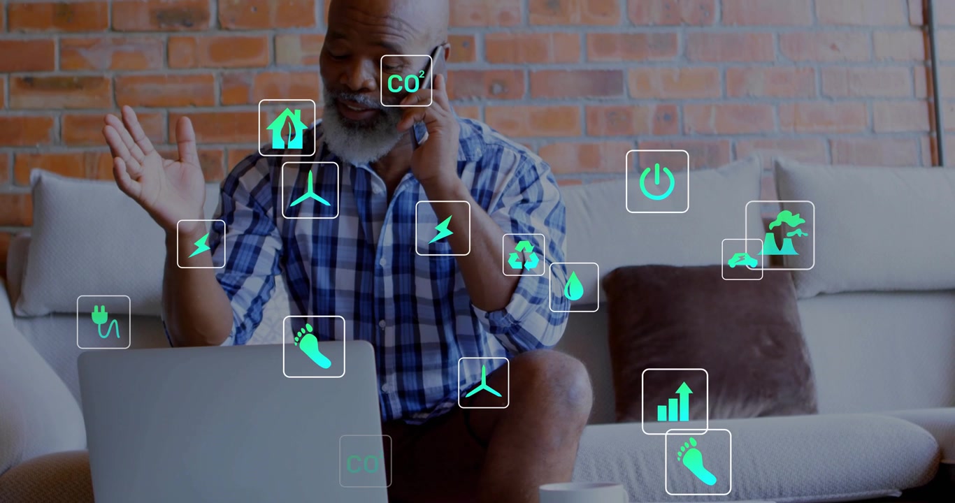 Receiving call gray-bearded man in plaid at home discussing energy, gesturing by laptop icons