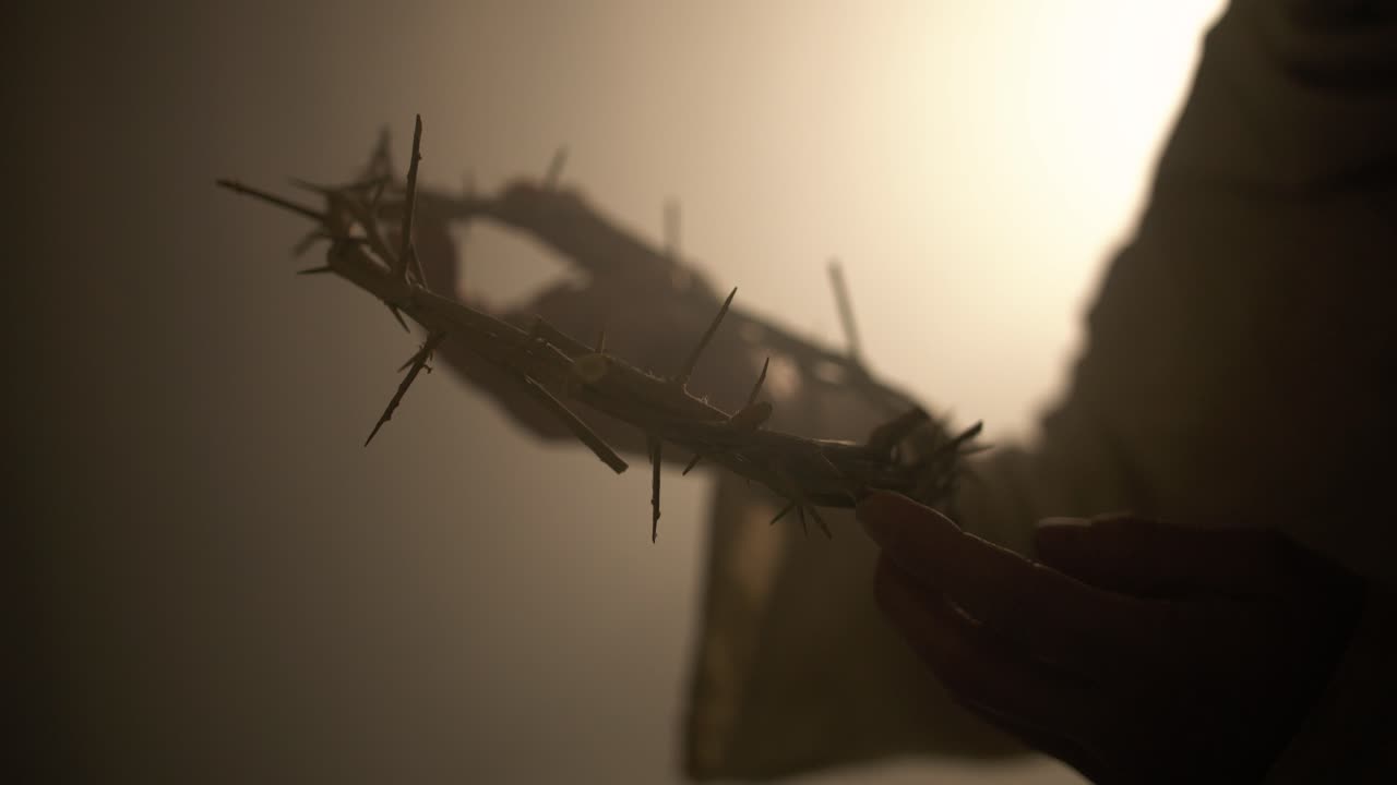 Jesus Christ holding a crown of thorns in ambient, glowing light as visual representation of good Friday and the crucifixion of Jesus on the cross. Perfect for Easter visual or gospel symbolism.