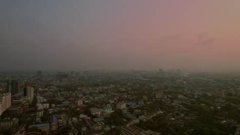 hazy dusk over bangkok's sprawling cityscape - aerial flyover