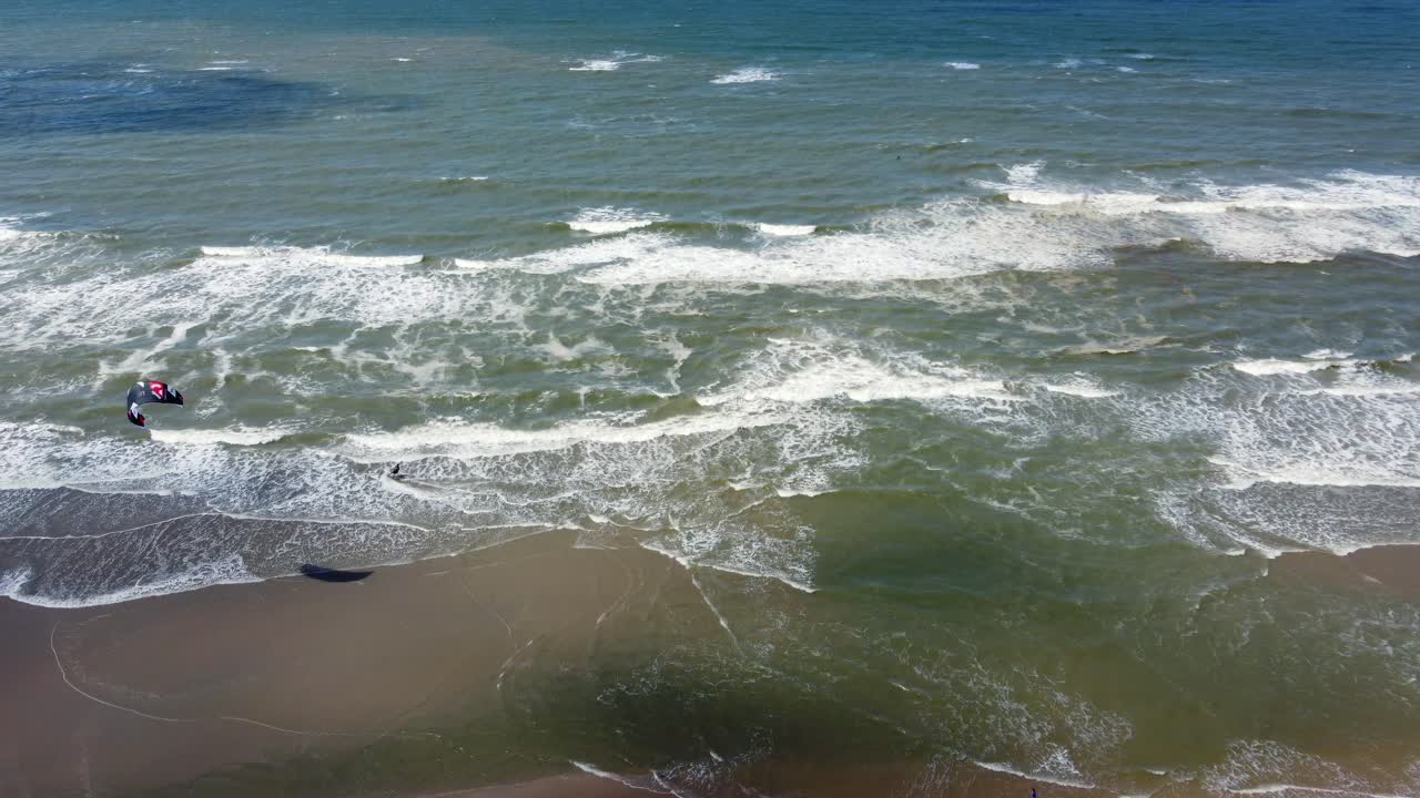 kiteboarding y surf en el agua de una pintoresca costa, aérea