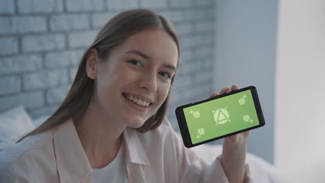 retrato de una mujer joven y bonita sosteniendo un teléfono con pantalla verde de maqueta