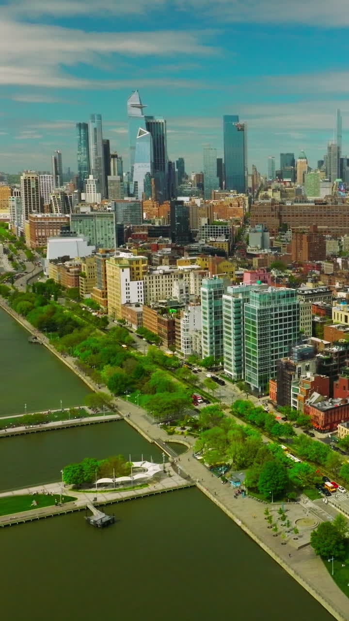 Colorful bright architecture of New York at sunny weather day. Beautiful parks at the waterfront of the river. Skyscrapers at backdrop. Vertical video