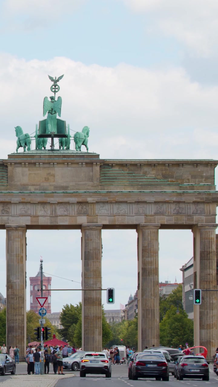 Et bredt panorering viser den historiske Brandenburger Tor med trafik og fodgængere i Berlin.