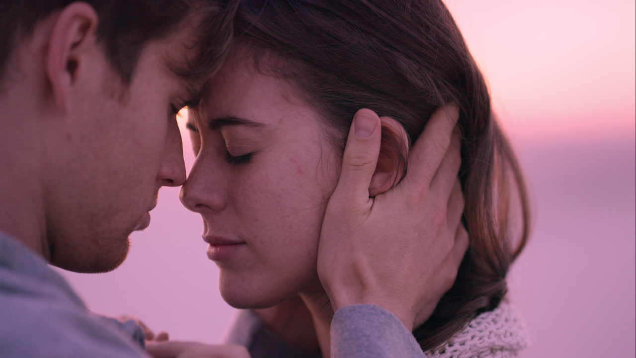 슬픈 여자는 해가 지는 해변에서 파트너에 의해 위로를 받고 화가 납니다.