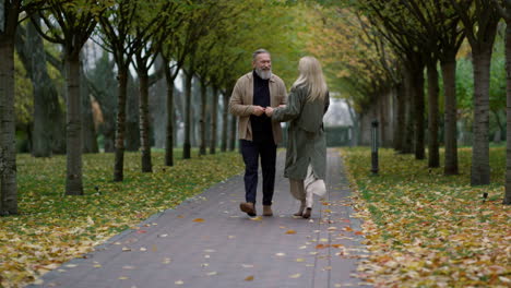 wide shot of smiling happy couple having fun in beautiful foliage park.