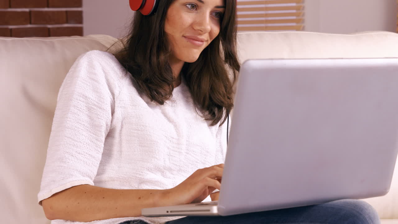 Smiling woman using laptop on sofa