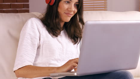 mujer sonriente usando una laptop en el sofá