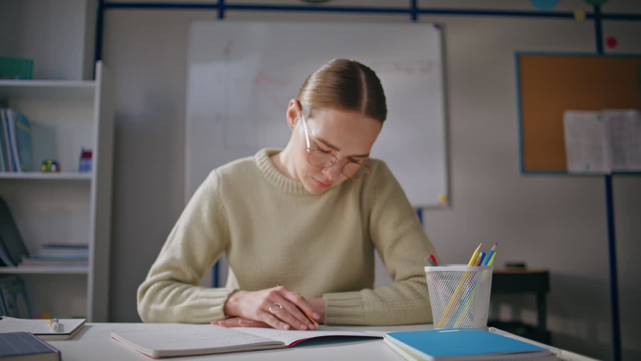 Serious teacher working school closeup. Young woman checking homework at class