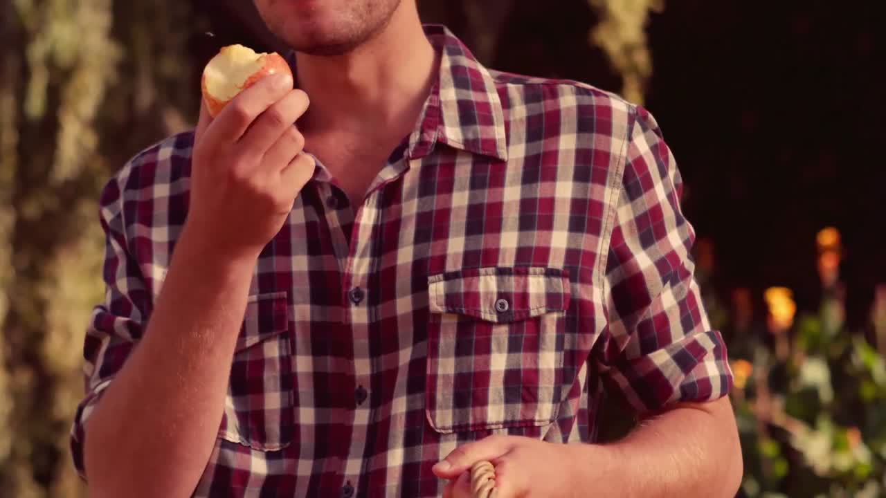 feliz granjero sosteniendo una canasta de manzanas y comiendo manzanas