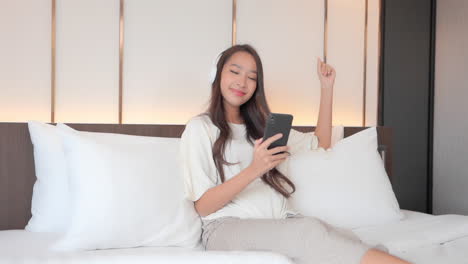 attractive young woman listening to music on the bed with smartphone