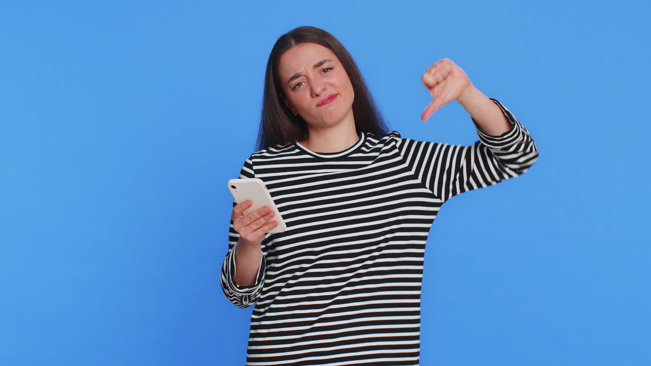 슬프고 화가 난 여성은 스마트폰을 사용하며 게임을 하고, 패배하고, 실패하고, 불행한 소식, 나쁜 복권 결과, 위기를 겪는다.