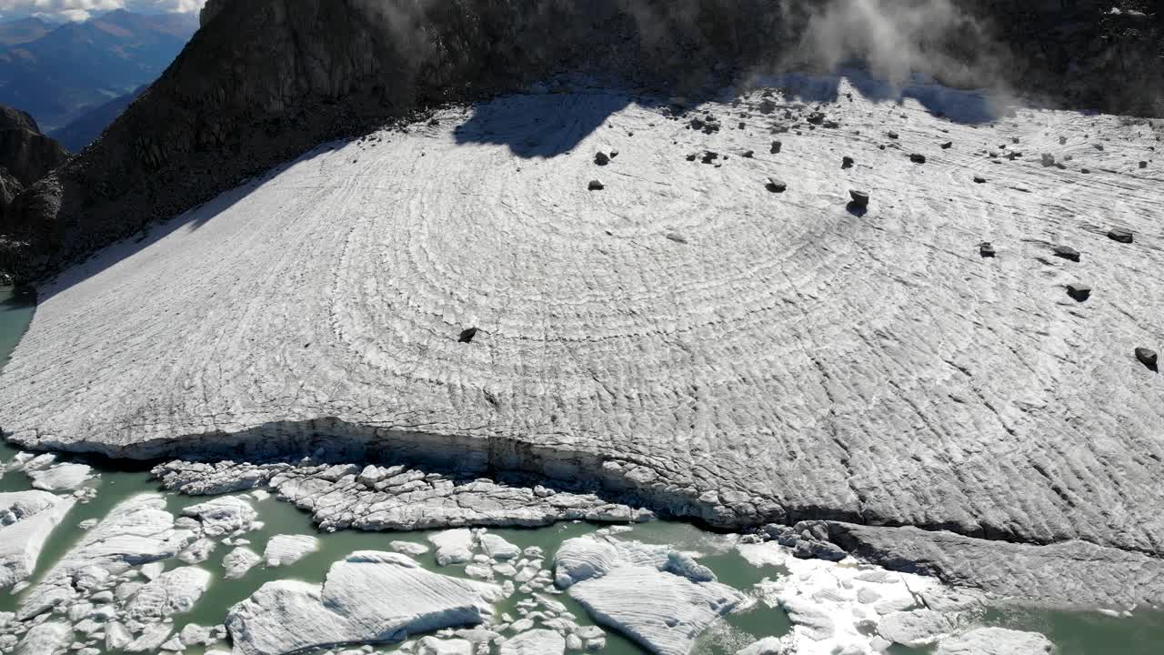 화창한 날 스위스 알프스의 외딴 지역에서 녹은 빙산으로 가득 찬 호수를 드러내는 빙하 위의 공중 비행