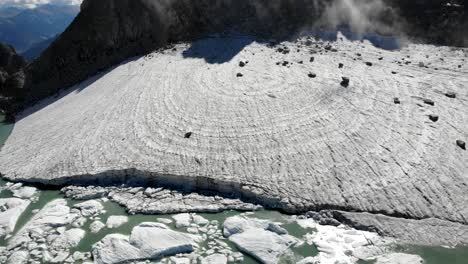 sobrevuelo aéreo sobre un glaciar que revela un lago lleno de icebergs derretidos en partes remotas de los alpes suizos en un día soleado
